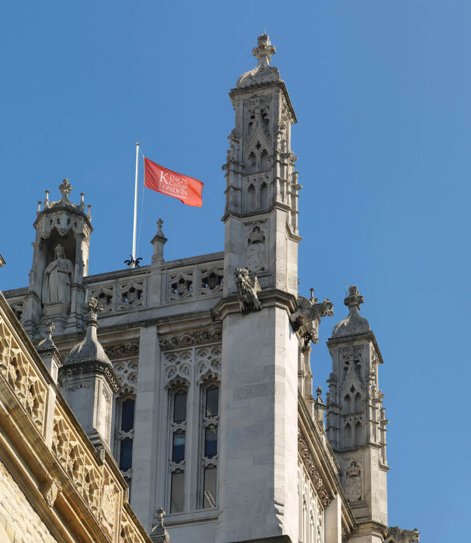 Side view of the Maughan Library clock tower with a King's flag